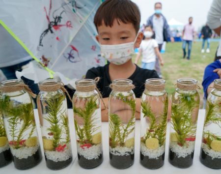 (miniature) Un garçon observe des micro-écosystèmes dans des bouteilles exposées lors d'une activité ayant pour thème la conservation du fleuve Yangtsé