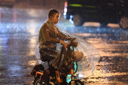 (miniature) Un homme sur un vélo électrique sous la pluie
