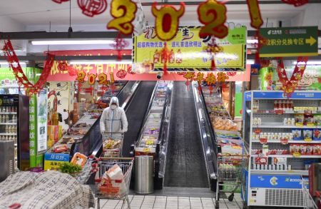 (miniature) Un bénévole achète des produits de première nécessité selon les commandes en ligne des habitants en quarantaine dans un supermarché de l'arrondissement de Dongchang de Tonghua