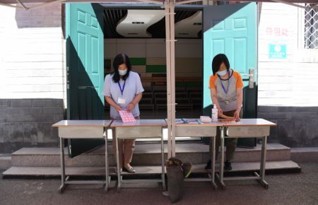 (miniature) Des membres du personnel préparent des bureaux de dépôt de sacs à main dans un site d'examen national d'entrée à l'université