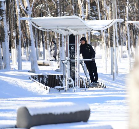 (miniature) Un homme fait des exercices après la neige dans le Parc olympique à Shenyang
