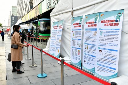 (miniature) Des habitants lisent des affiches donnant des directives de vaccination dans une installation mobile de vaccination contre le COVID-19 près du quartier des affaires de Xidan
