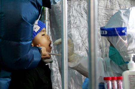(miniature) Un travailleur médical prend un échantillon de gorge sur un garçon pour le test d'acide nucléique de la COVID-19 dans un site de test dans l'arrondissement de Fengtai à Beijing