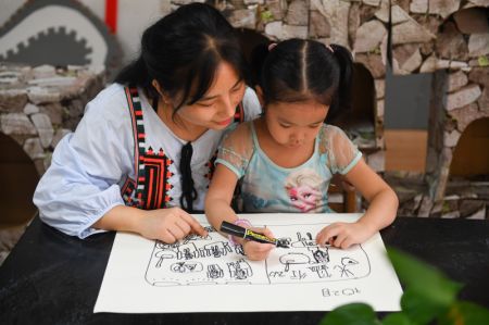 (miniature) Une enseignante apprend à une fillette à dessiner un tableau sur la frugalité alimentaire dans un jardin d'enfants à Changsha