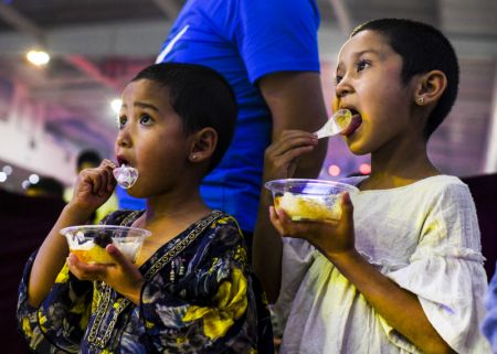 (miniature) Des enfants dégustent des snacks dans un marché de nuit à Hotan