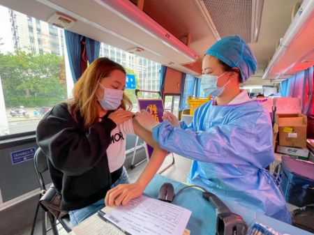 (miniature) Une femme se fait vacciner contre la COVID-19 à bord d'un véhicule de vaccination mobile près d'un centre d'affaires à Nanjing