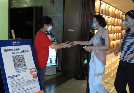 (miniature) Une employée contrôle les codes de suivi sanitaire des spectateurs dans un cinéma UME à Shanghai